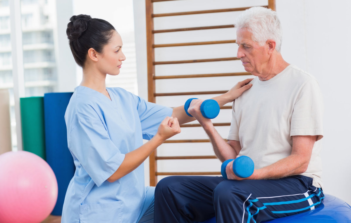 caregiver assisting senior man in exercise