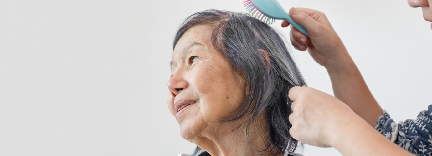 a person combing the hair of senior woman