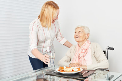 adult woman preparing meal for senior woman 