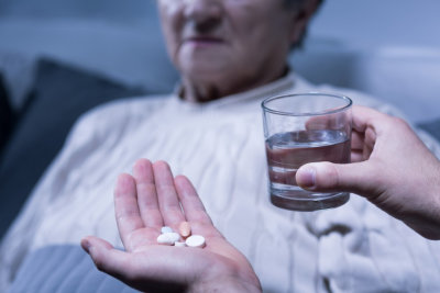 a person holding some pills and a glass of water