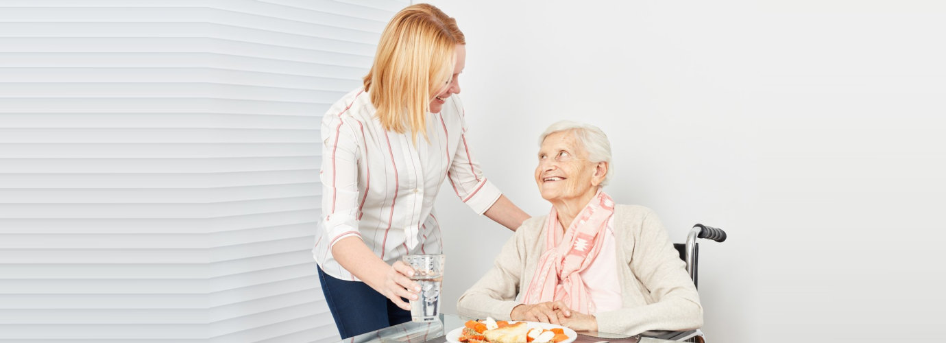 adult woman preparing meal for senior woman