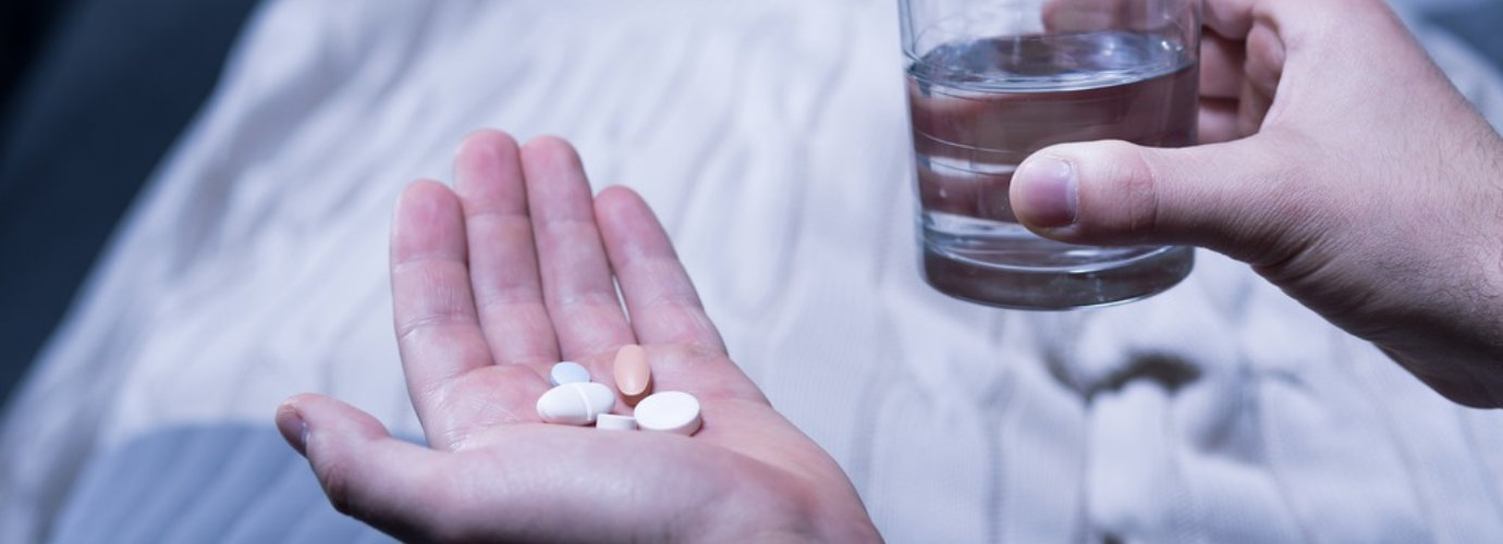 a person holding some pills and a glass of water